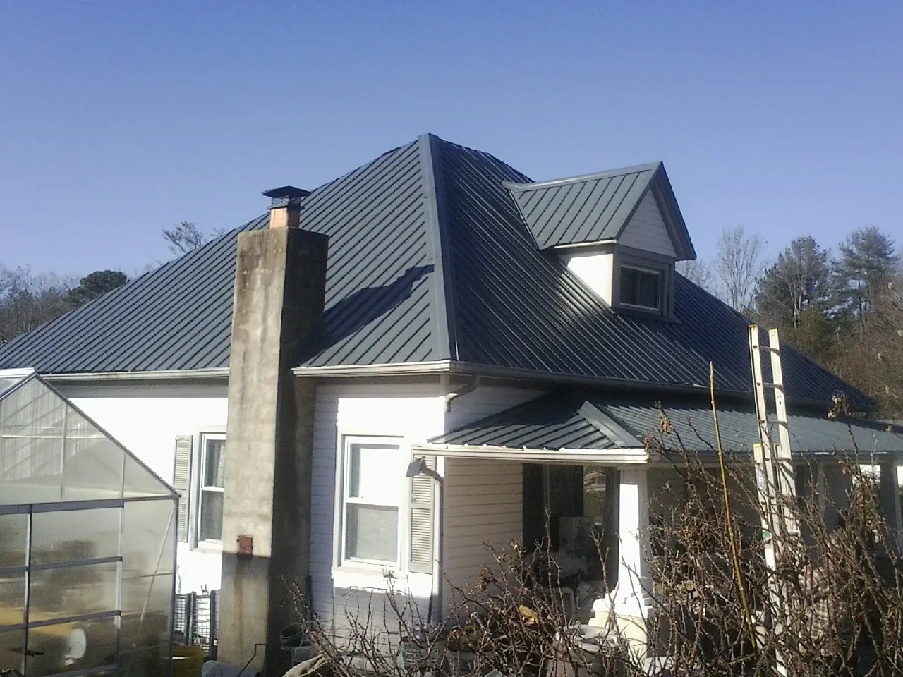 Dark blue standing seam metal roof on a white farmhouse with dormer — Slate & Tile Roof Repair by Roofing Brothers in Waco