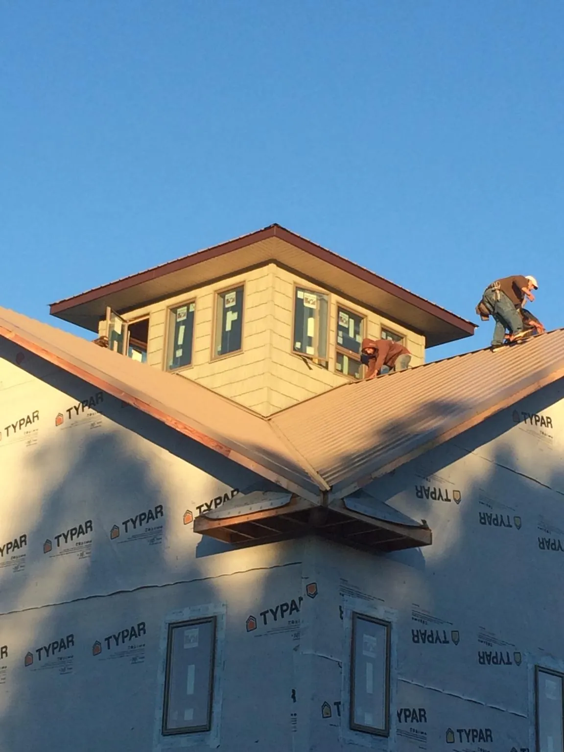 Roofers working around a rooftop cupola on a new metal roof at sunset — Roof Waterproofing in Waco by Roofing Brothers